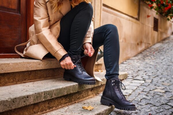 Woman,Wearing,Trench,Coat,Sitting,On,Staircase,And,Tying,Shoelace