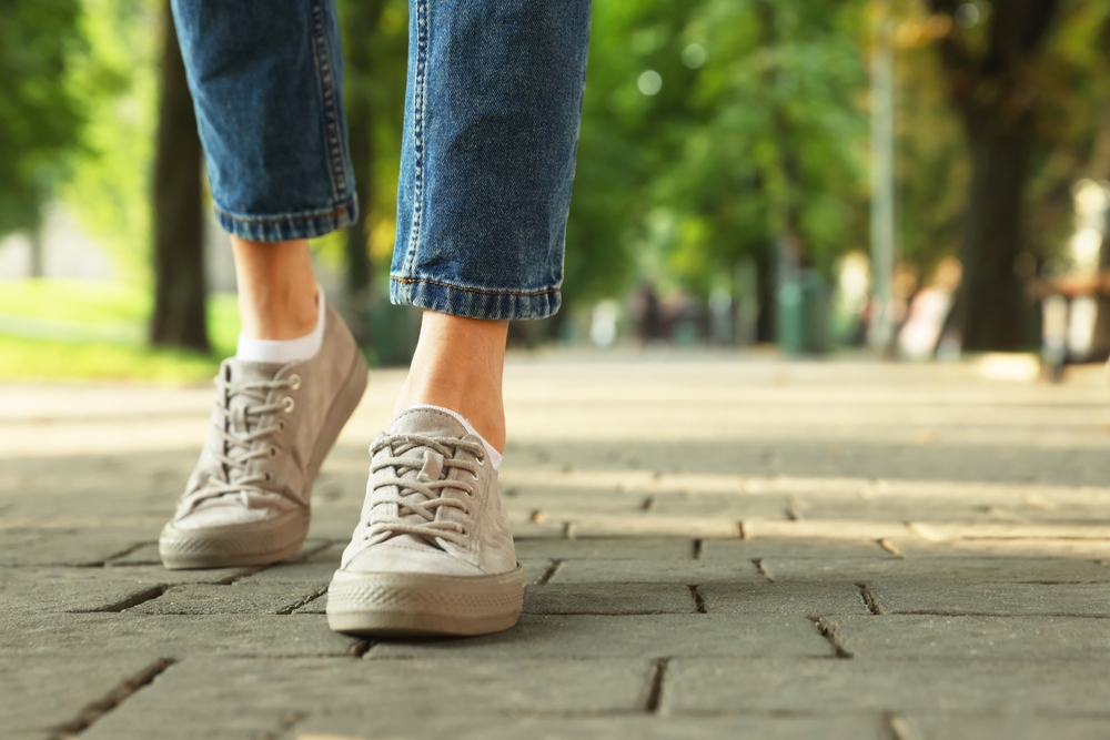 Woman,In,Stylish,Sneakers,Walking,On,City,Street,,Closeup.,Space